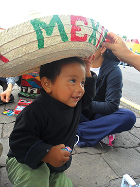 Vision 2017 Scheiber 6 Street-wise sisters on a roll Volunteers surprise one of their youngest visitors with a traditional Mexican sombrero.