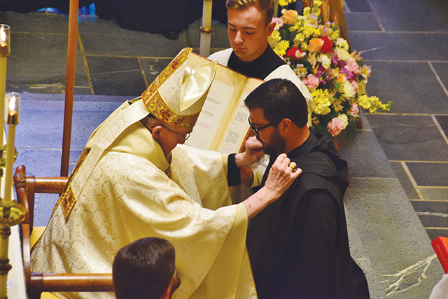Vision 2024 Pautler 3 Monastic life is habit-forming The abbot of the monastery places the hood, or capuche, around the shoulders of Brother Pachomius Alvarado, O.S.B. during his profession of temporary vows.