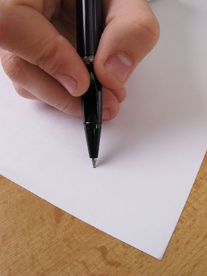 hand holding a pen writing on paper hand holding a pen writing on paper