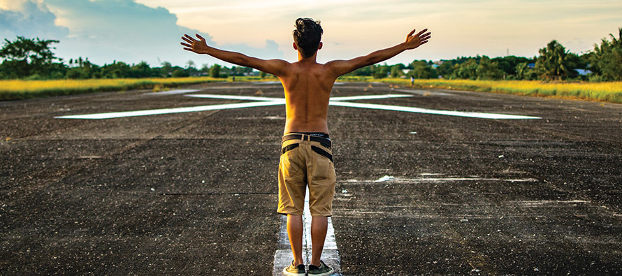 Young man standing in road with his arms open wide